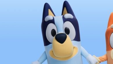 Bluey, now starring at Animal Kingdom’s virtual queue, smiles and holds hands with Bingo on a vibrant blue backdrop.